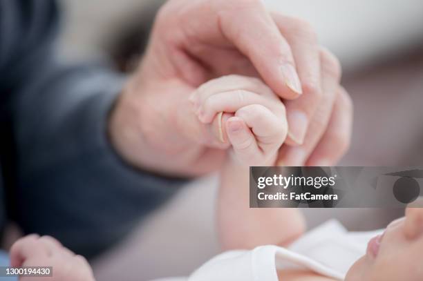 an elderly hand holding a newborn's hand - old life new life stock pictures, royalty-free photos & images