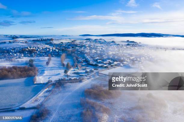 the aerial view from a drone of a small scottish town on a misty winter morning after a fall of snow - scotland winter stock pictures, royalty-free photos & images