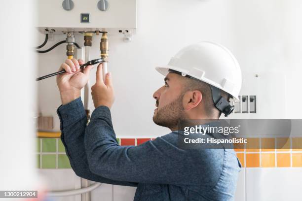 repairman installing a natural gas boiler at a house - repairing stock pictures, royalty-free photos & images