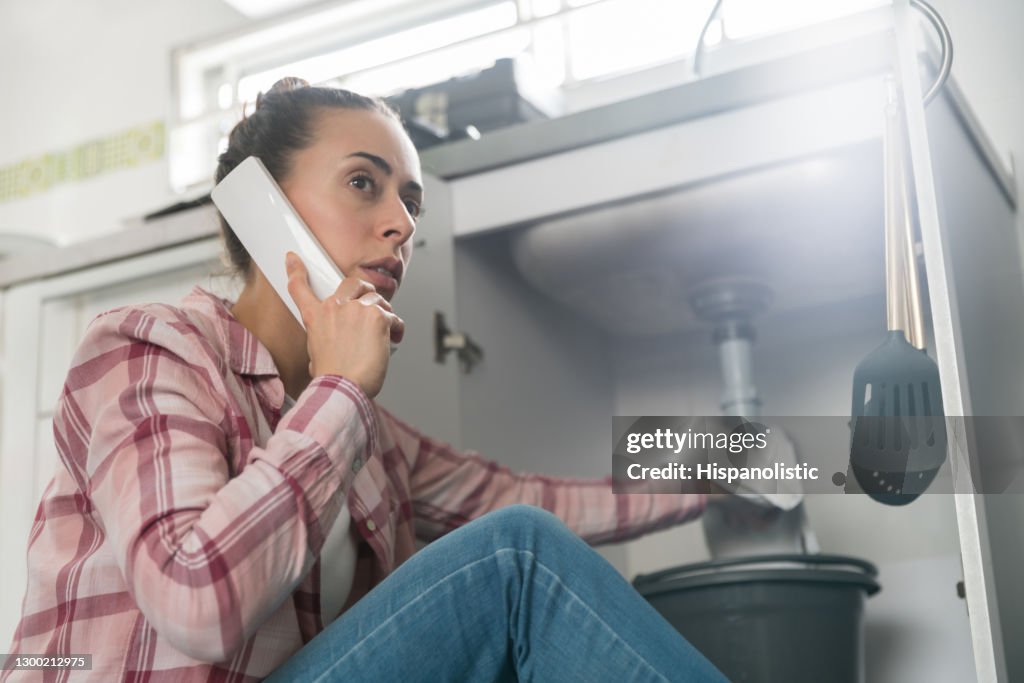 Donna a casa che chiama un idraulico per una pipa che perde nel lavandino