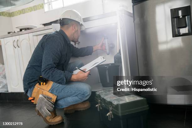 loodgieter die een probleem met de gootsteen in de keuken bevestigt - loodgieter stockfoto's en -beelden