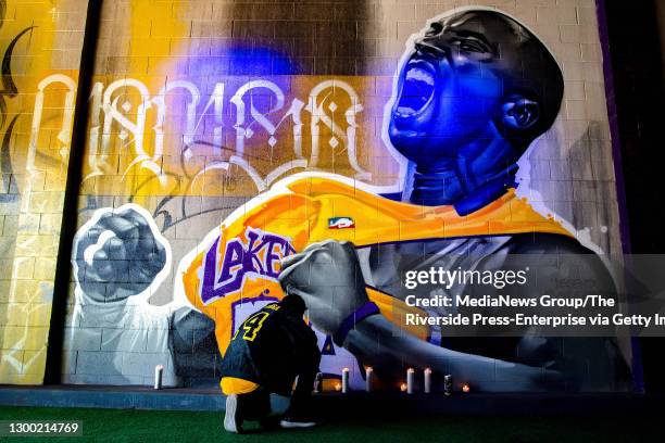 Marco McGuire, owner of Downtown Experiment, lights a candle as he pays his respect for Kobe Bryant in front of a mural painted by artist Rudy Mendez...