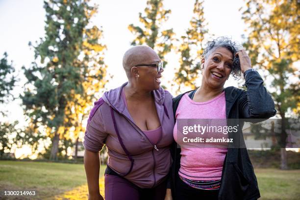 two black woman walking through a grass field - fat lesbian stock pictures, royalty-free photos & images