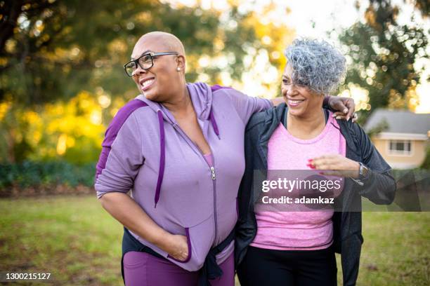 two black woman walking through a grass field - fat lesbian stock pictures, royalty-free photos & images