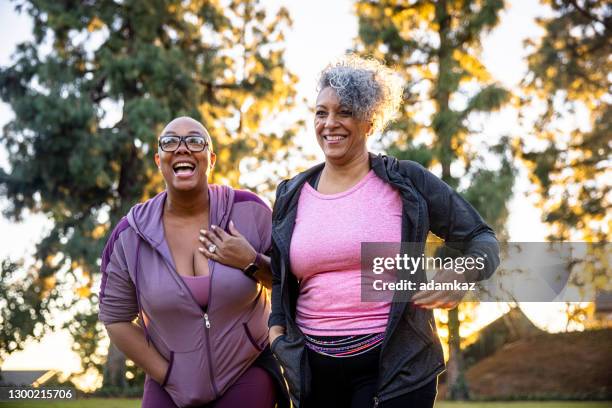 zwei schwarze frau zu fuß durch ein grasfeld - alte und junge lesbische frauen stock-fotos und bilder