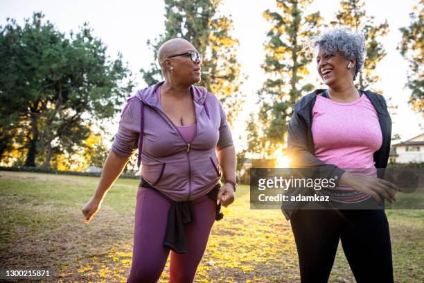 due donne di colore che camminano attraverso un campo di erba - ginnastica foto e immagini stock