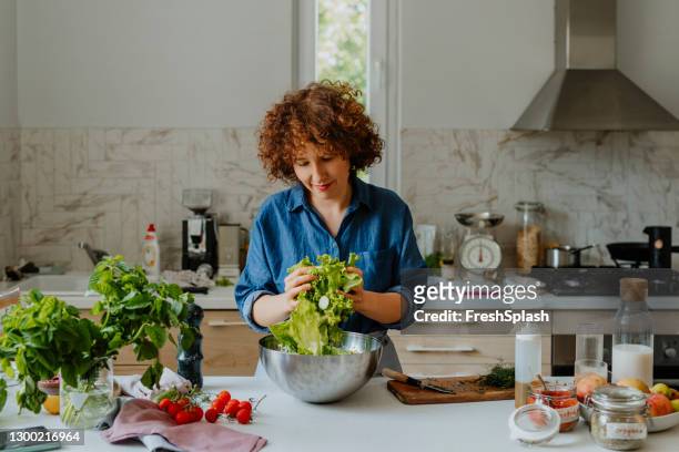 happy woman tossing a salad in the kitchen (copy space) - salad dressing stock pictures, royalty-free photos & images