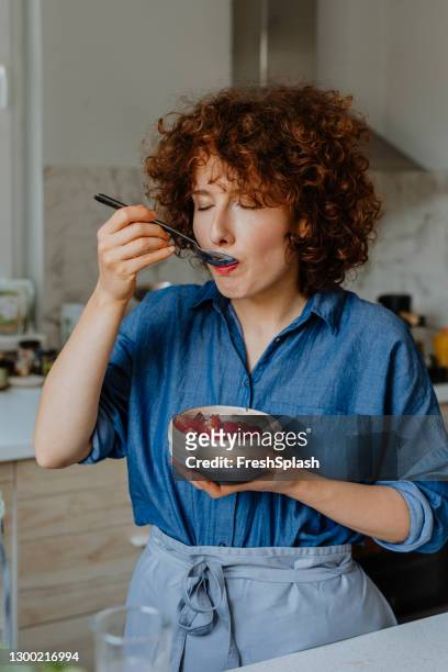 gelukkige vrouw die een kom van heerlijke havermout met fruit voor ontbijt eet - blue bowl stockfoto's en -beelden