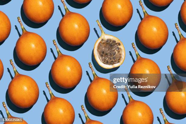 yellow sweet passion fruits (granadilla, passiflora ligularis) and one halved fruit on the blue background - maracuja stock-fotos und bilder