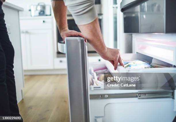 hombre irreconocible buscando comida en el cajón del congelador - congelador fotografías e imágenes de stock