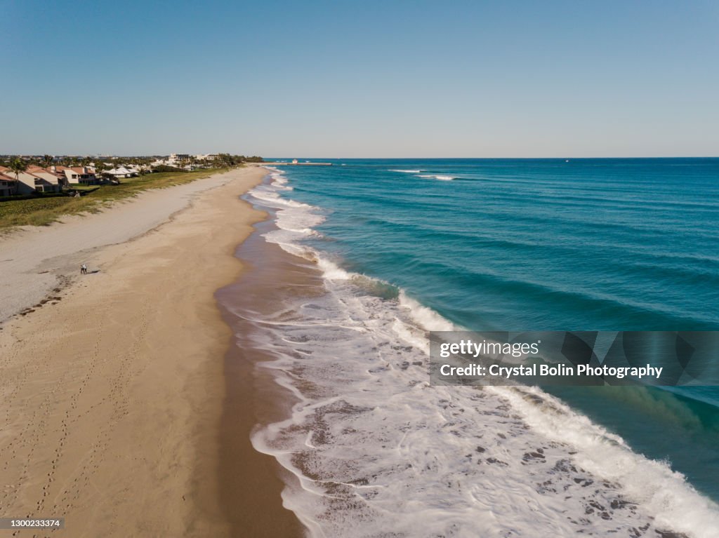 Luftdrohnenansichten von tealfarbenen Wellen, die an einem Wochentag im Februar 2021 über den Boynton Beach, Florida Seashore fegen