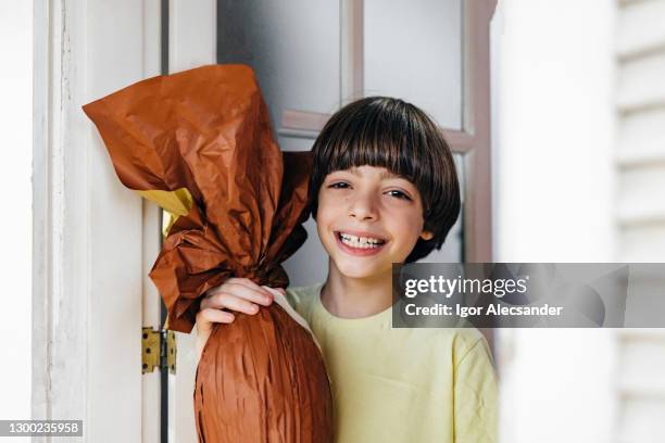 happy boy holding an easter egg - chocolate easter egg stock pictures, royalty-free photos & images