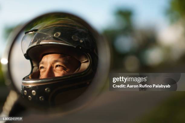 southeast asian man's happy eyes inside motorcycle helmet reflected on side mirror - motorcycle rider 個照片及圖片檔