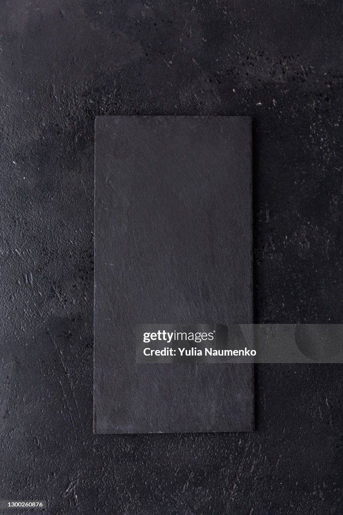 Black slate stone cutting board on wooden background