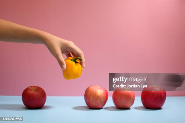 hand picking apple from row to illustrate choice and decision - concepts & topics stockfoto's en -beelden