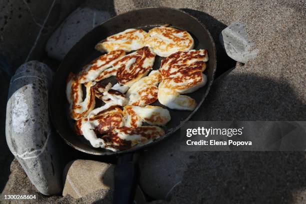 traditional cyprus halloumi cheese grilled on the hot stones at the beach - grilled halloumi stock pictures, royalty-free photos & images