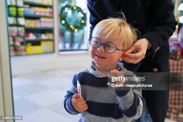 young mother choosing prescription glasses for her baby boy - miopia foto e immagini stock
