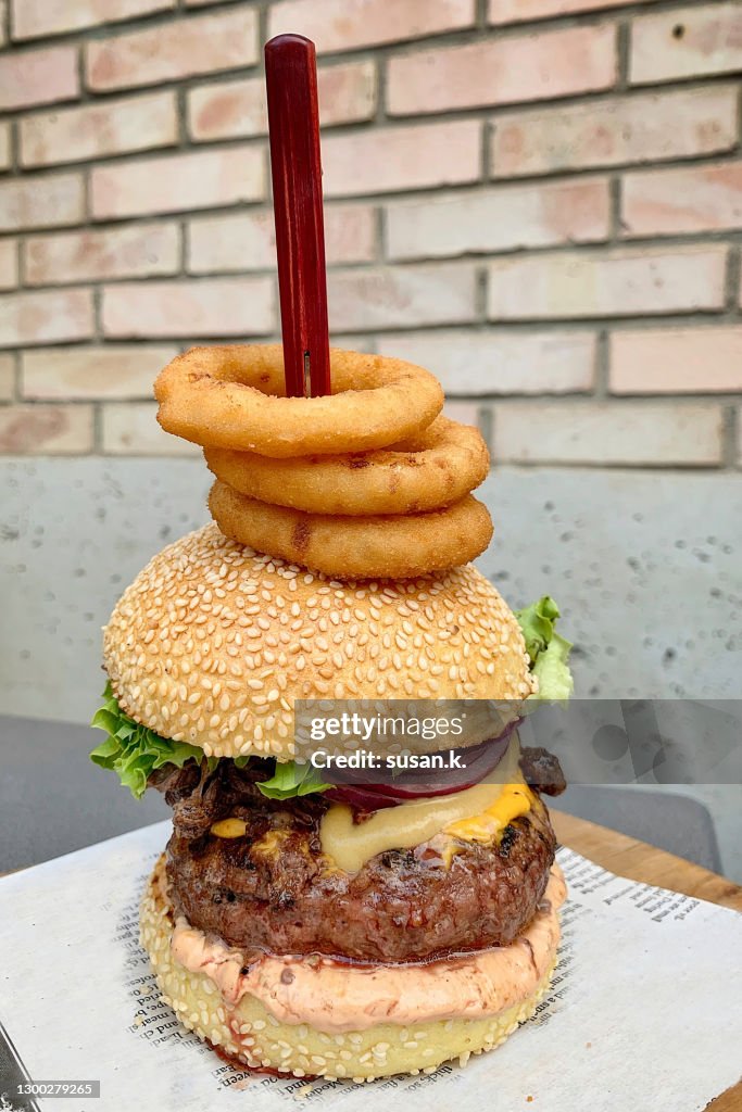 Close up shot of gourmet hamburger with stacked onion rings.