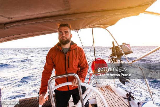 man at the steering wheel on the yacht at sunset. luxury vacation at the sea - sailor foto e immagini stock