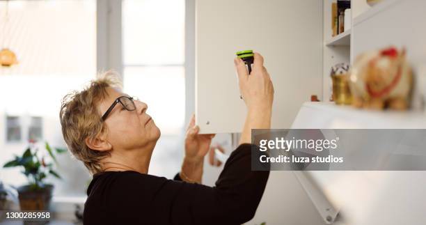 mujer mayor buscando su medicación en el gabinete - escaparate fotografías e imágenes de stock