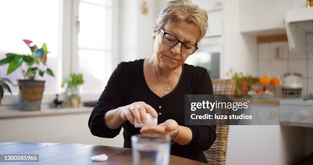 hogere vrouw die pillen neemt - pillen nemen stockfoto's en -beelden