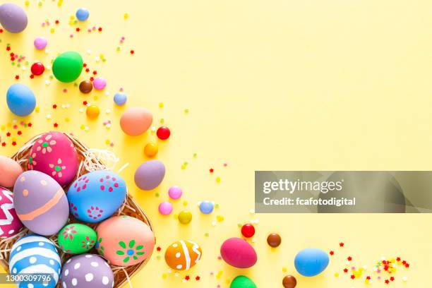 ovos de páscoa coloridos com doces e granulado de açúcar em fundo amarelo. copiar espaço - easter basket - fotografias e filmes do acervo