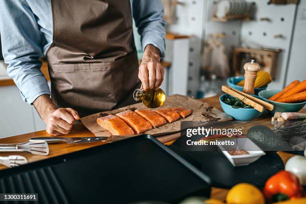 junger mann bereitet lachssteak zum braten vor - avocato oil stock-fotos und bilder