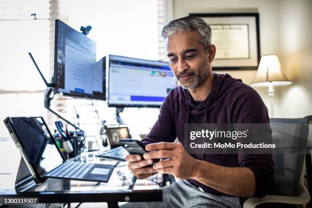 man working in home office - asian and indian ethnicities fotografías e imágenes de stock