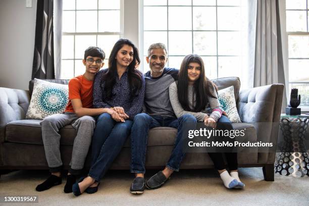 portrait of family in living room at home - portrait of family sitting on sofa together stock pictures, royalty-free photos & images