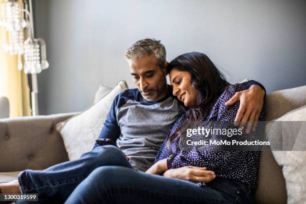 husband and wife embracing on couch - indian woman phone stock pictures, royalty-free photos & images
