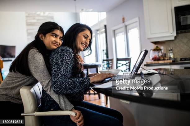 woman working from home in kitchen while teenager daughter distracts her - asian mother daughter stock pictures, royalty-free photos & images