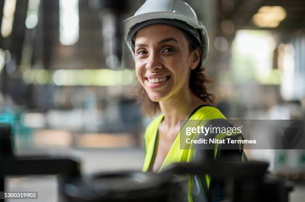 smiling latin women engineer in auto part factory. her is looking smart and confidence. - industrial portrait stockfoto's en -beelden
