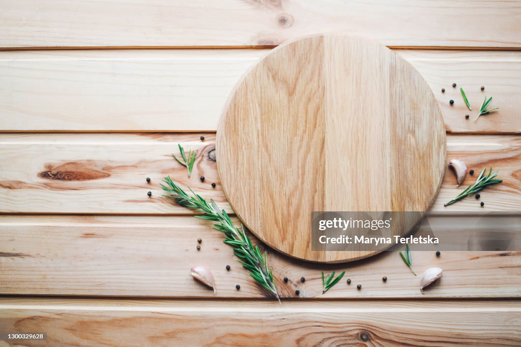 Round cutting board with spices on a wooden background.