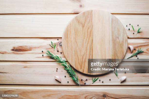round cutting board with spices on a wooden background. - board fotografías e imágenes de stock