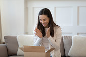 Excited young woman shopper unboxing parcel shipped by mail