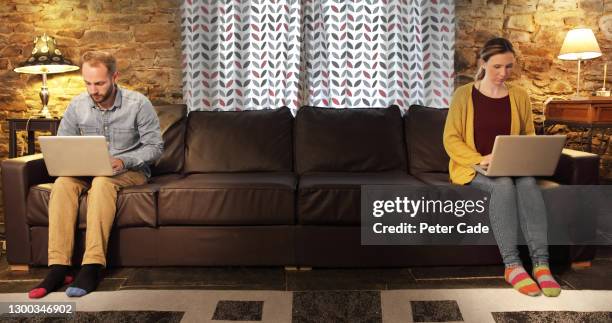 couple sat at opposite ends of sofa on laptops - couple on sofa stock pictures, royalty-free photos & images