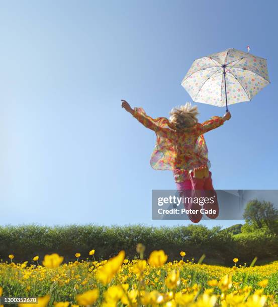 woman jumping with umbrella in field of flowers - vertical jump stock pictures, royalty-free photos & images