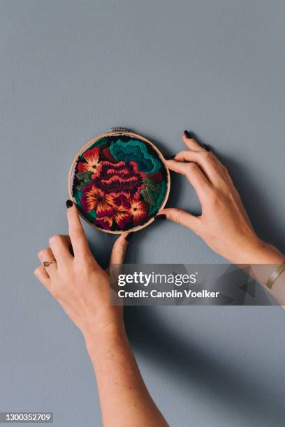 human hands holding a embroidery frame to a blue wall - embroidery frame stock pictures, royalty-free photos & images