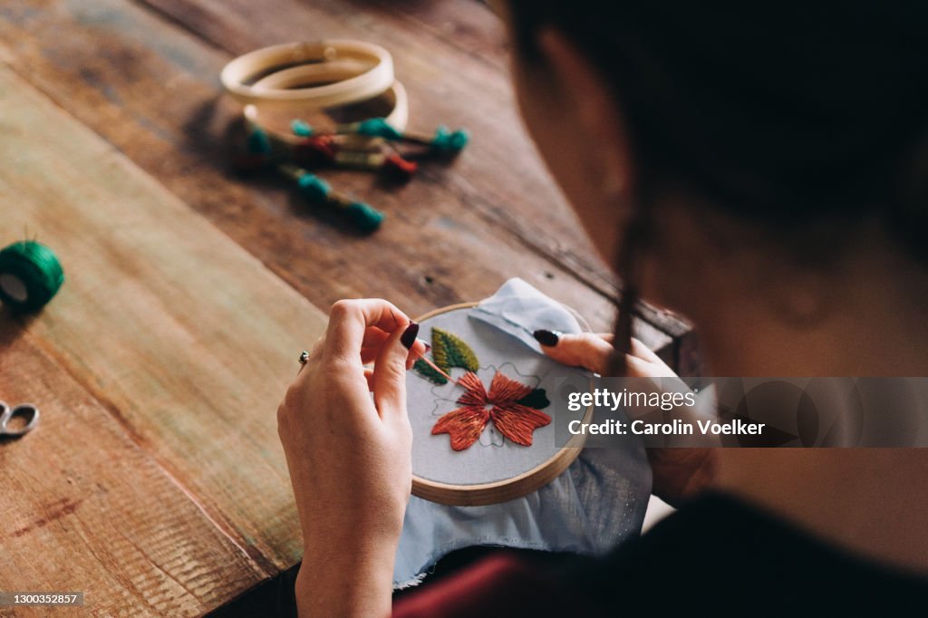 View over shoulder of a woman doing embroidery and colourful needlework