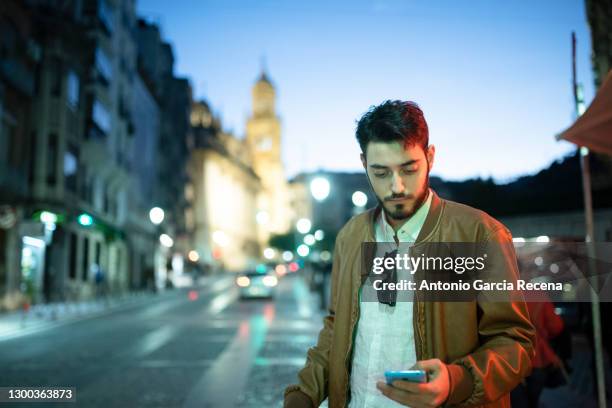 young man in the city night using phone with night eurpean city backgrund - jaén city stock pictures, royalty-free photos & images