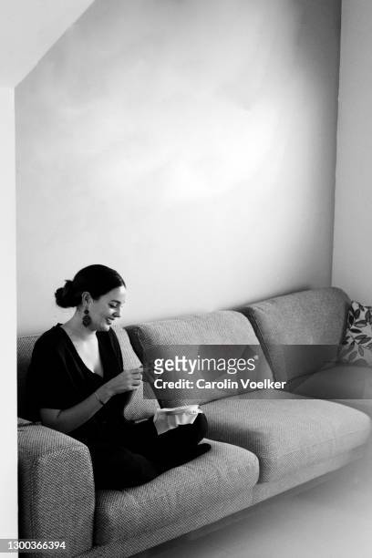 black and white image of young woman sitting on a couch doing crafts - mexico black and white stock pictures, royalty-free photos & images