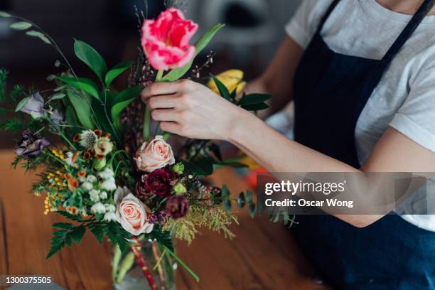 cropped shot of young woman arranging fresh flowers at home - florest stock pictures, royalty-free photos & images