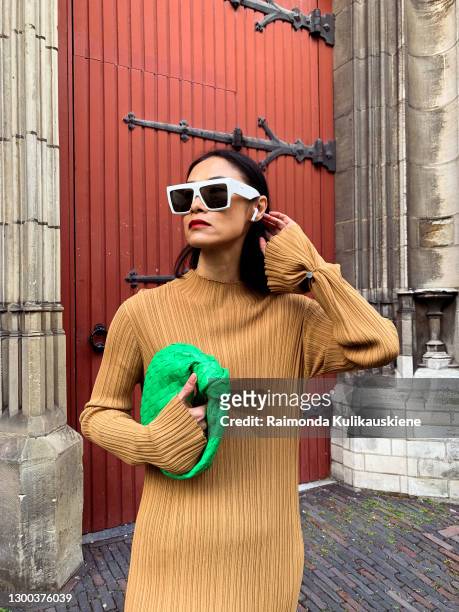 Pornwika Spiecker wearing Holzweiler dress, Ann Demeulemeester boots, Bottega Veneta bag and Celine sunglasses poses during an online street style...