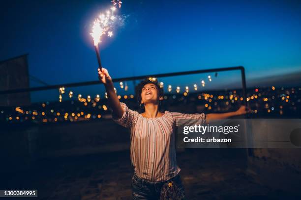 junge frau mit funkeln auf dem dach - summer party lights stock-fotos und bilder