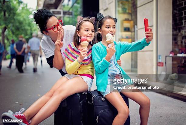 mother and daughters are taking selfie/making video call on the street - hungary summer stock pictures, royalty-free photos & images