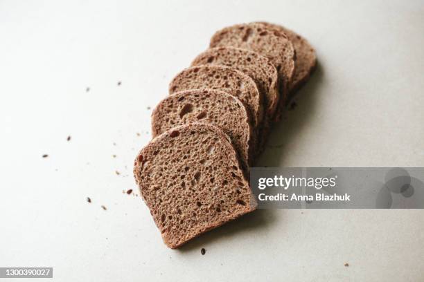 sliced dark loaf of bread and flax seed and crop over beige natural background - sliced bread stock pictures, royalty-free photos & images