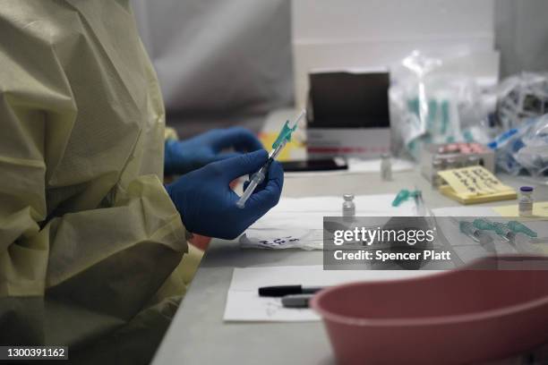 Pharmacist prepares vaccine doses as people receive a COVID-19 vaccination shot at a pop-up site at a Bronx church on February 04, 2021 in New York...
