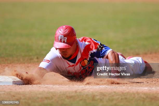 Juan Centeno #of Puerto Rico slides safely into first base on the 5th inning during the game between Panama and Puerto Rico as part of Serie del...