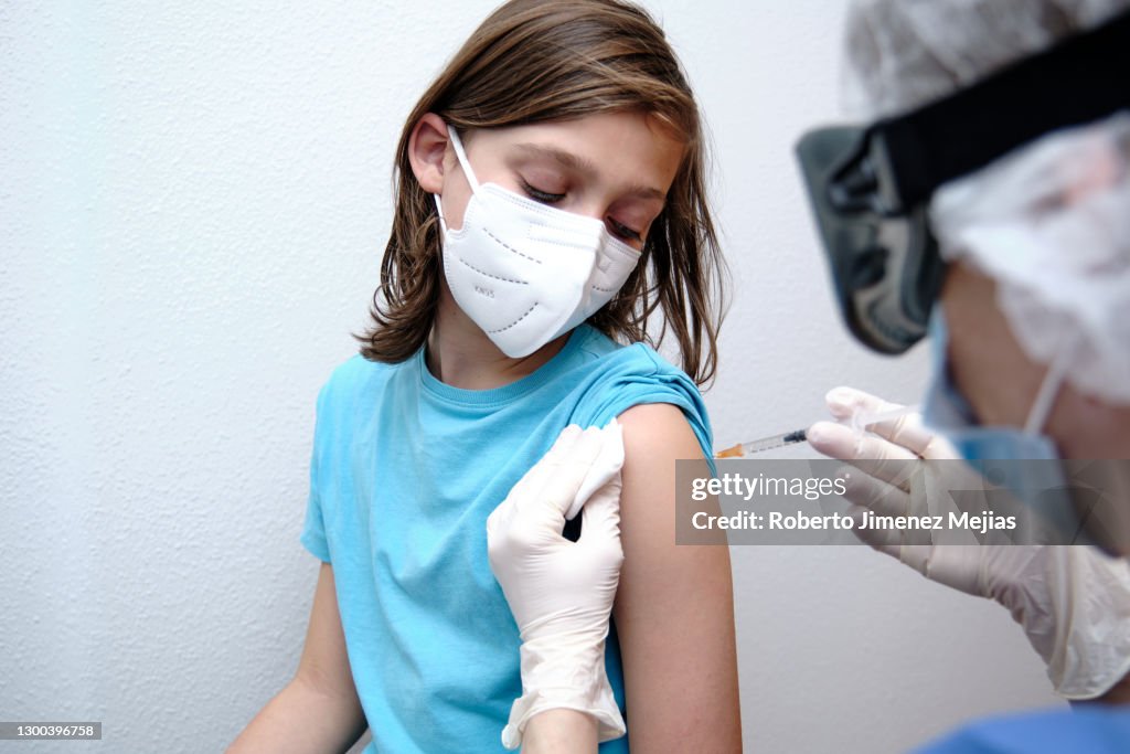 Female doctor giving covid-19 vaccine to a boy