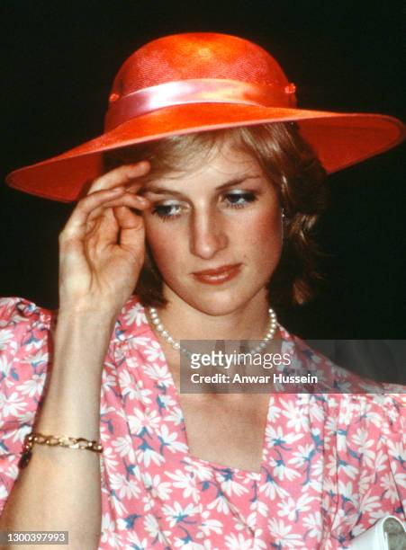 Diana, Princess of Wales, wearing a pink dress with a floral pattern designed by Bellville Sassoon and a pink hat designed by John Boyd, listens to a...